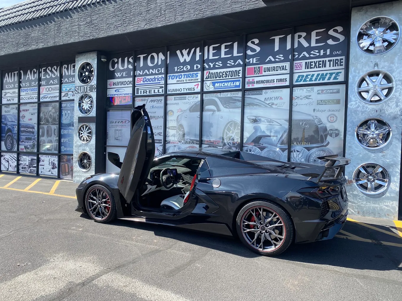 Black Corvette C8 with vertical doors, Hyper Silver custom wheels with red accent stripe and real carbon fiber high-rise rear wing