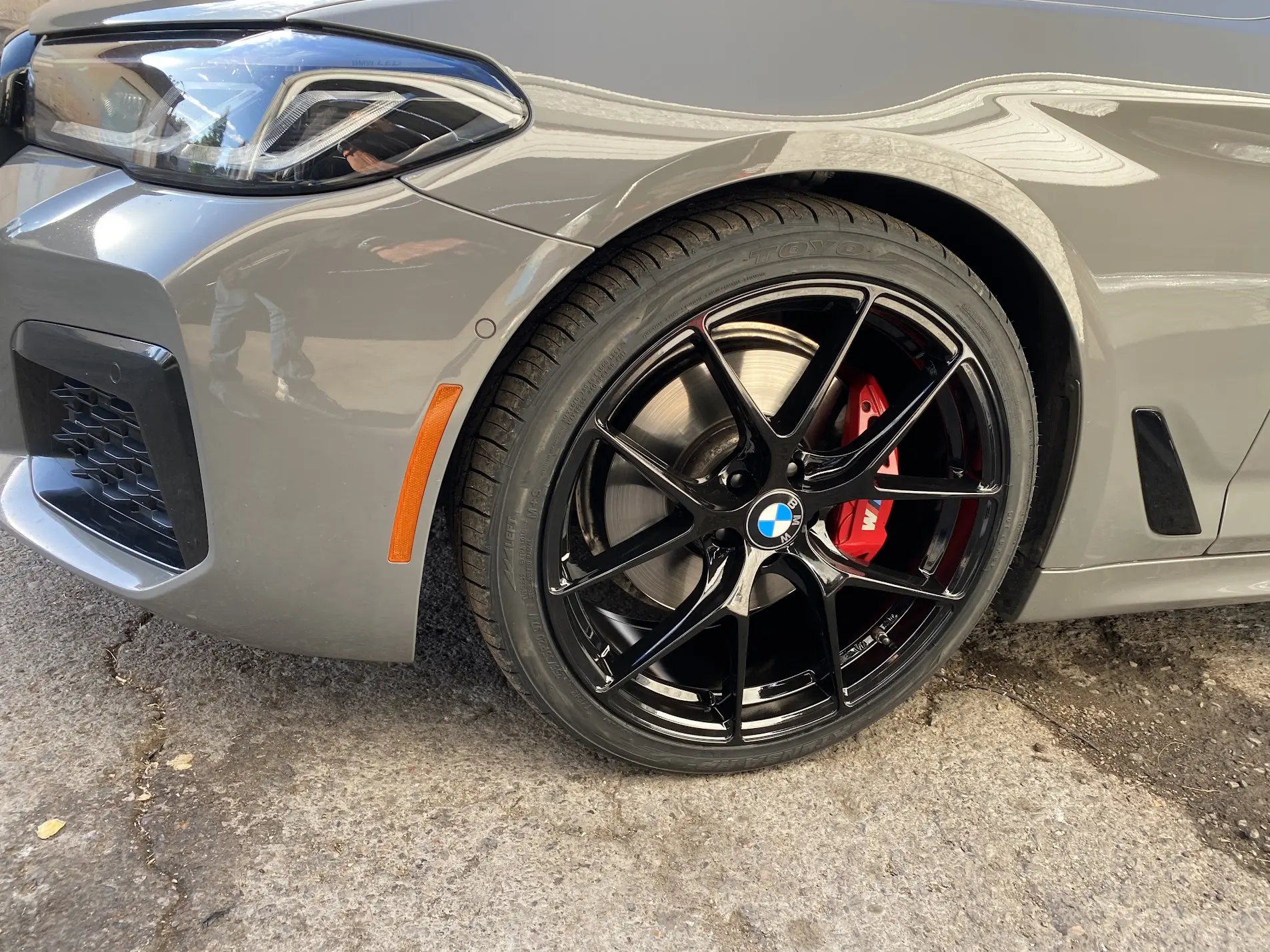 Close-up of a BMW on gloss black wheels with red brake calipers