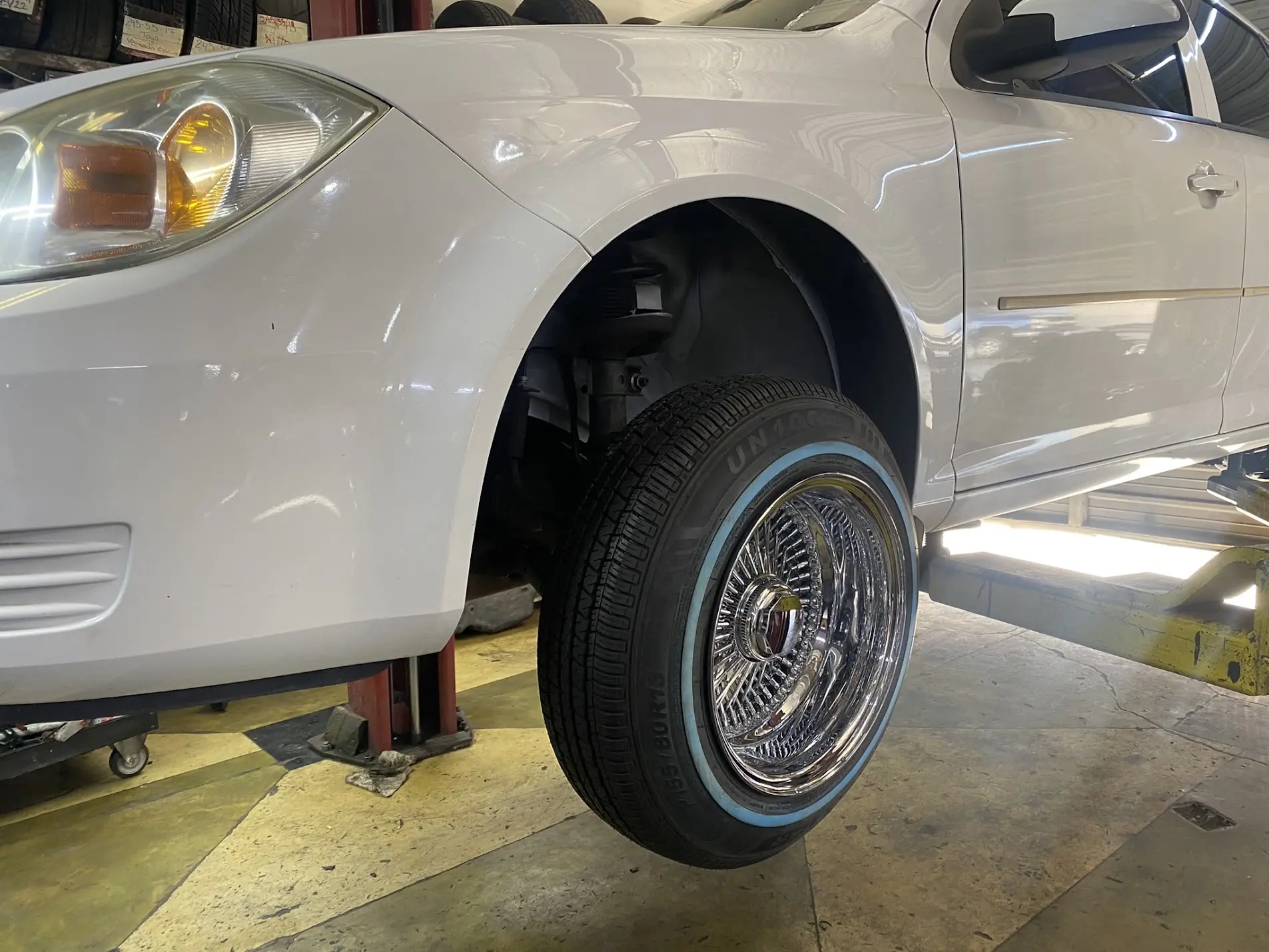 White sedan on 13-inch 100-spoke knockoff wire wheels with 155/80R13 whitewall tires