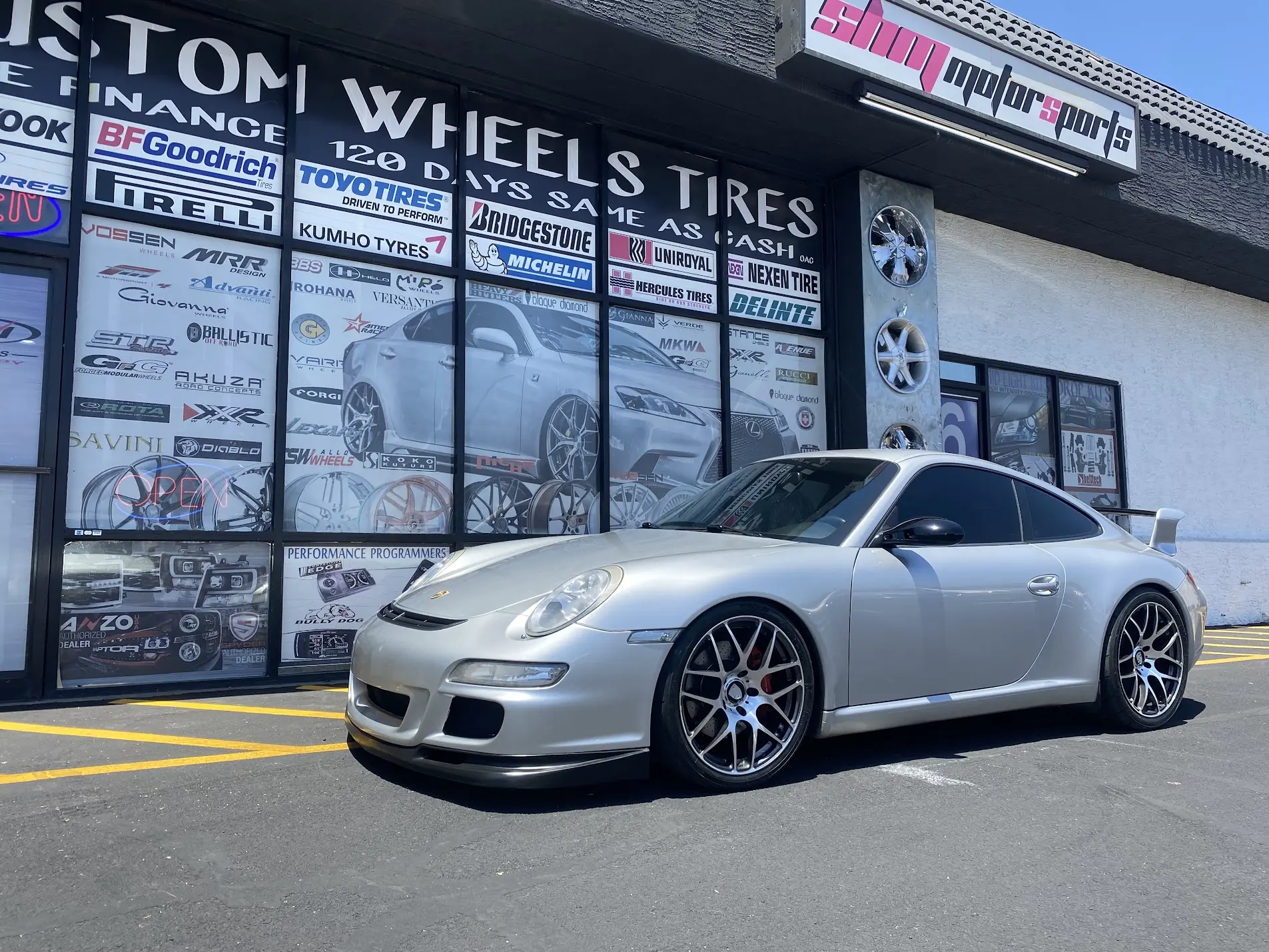Silver 2007 Porsche 911 on custom wheels parked in front of SHM Motorsports