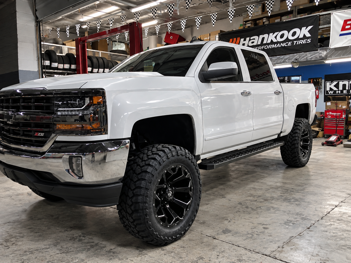 2017 Chevrolet Silverado in white with a 4-inch lift kit, 20x10 wheels, 35x12.50R20 mud-terrain tires and side steps